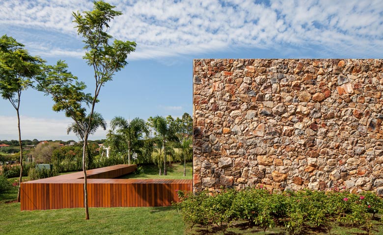 No interior paulista, projeto da Jacobsen Arquitetura, levemente suspenso do terreno, explora a madeira de brilho amazônico que faz a cabeça – e recobre as pranchetas – dos articuladores da nova casa brasileira